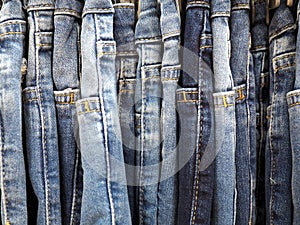 Row of worn blue jeans on a hanger in department store, close up