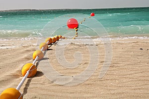 Yellow buoys on the sandy beach and in the water.