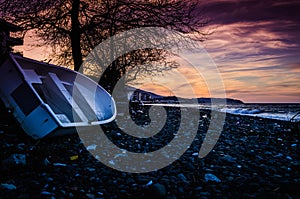 Rowboat Left On The Pebble Shore Sunset