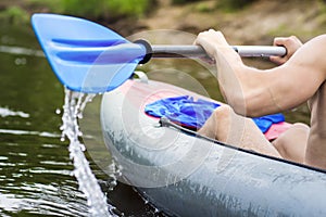 A rower in a boat with an oar. A man rafts on a kayak on the river. Rafting in a canoe with an oar. Active rest on the river