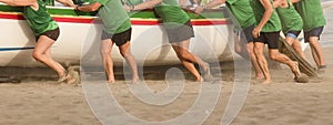 rowers push boat across the sand on the beach