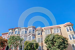 Rowhouses with bay windows and apartment building with sash windows in San Francisco, CA