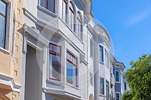 Rowhouses side view with painted walls across the trees against the sky in San Francisco, CA