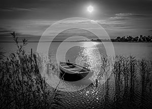 Rowing boat on lake at sunset, black and white.