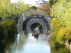Rowing a boat of tourists along canal area of Kurashiki, Japan. photo