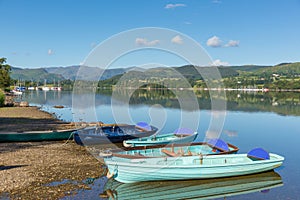 Rowing boats for hire for pleasure and leisure by beautiful lake and mountains on calm still day