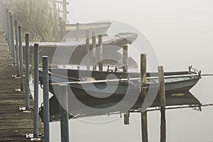 Rowing boats at a pier in river Oude IJssel on a misty day