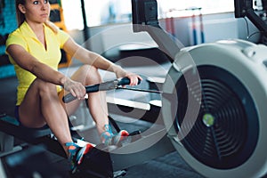 Rowing in the gym. Young woman training using rowing machine