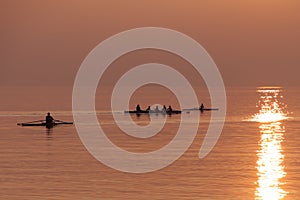 Rowing Team Training with Trainer over Shimmering Lake at Sunset