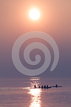 Rowing Team Training with Trainer over Shimmering Lake at Sunset