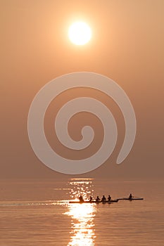 Rowing Team Training with Trainer over Shimmering Lake at Sunset