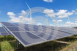 Rows array of polycrystalline silicon solar panels and wind turbines generating electricity in hybrid power plant systems station