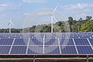 Rows array of polycrystalline silicon solar panels and wind turbines generating electricity in hybrid power plant systems station