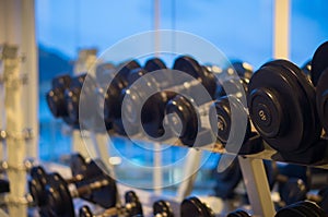 Rows of black dumbbells in the gym at evening