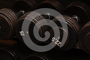 Rows of black iron dumbbells on a rack in gym, black