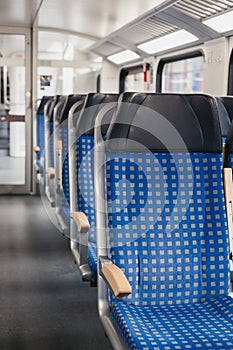 Rows of blue fabric seats inside empty modern train, travel concept, selective focus