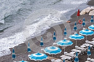 Rows of blue and white parasols and sunbeds on the beach at Atrani on the Amalfi Coast, Italy.