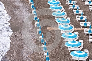 Rows of blue and white parasols and sunbeds on the beach at Atrani on the Amalfi Coast, Italy.