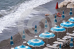 Rows of blue and white parasols and sunbeds on the beach at Atrani on the Amalfi Coast, Italy.