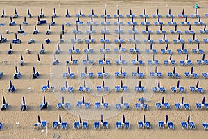 Rows of blue and white parasols and sunbeds on the beach. Italy