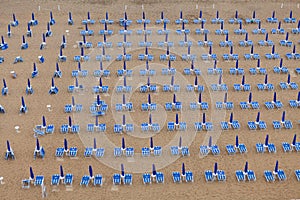 Rows of blue and white parasols and sunbeds on the beach. Italy