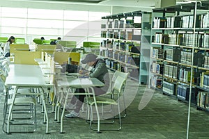 Rows of book racks and students in library