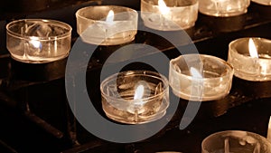 Rows of burning lit candles / tealights in Catholic Christian Church