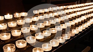 Rows of burning lit candles / tealights in Catholic Christian Church