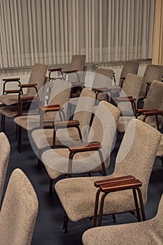 Rows of chairs made of metal and brown velour upholstery are empty in the building