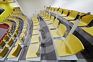 Rows of chairs and microphones in auditorium, side photo