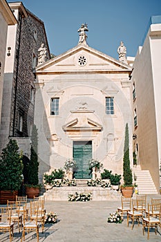 Rows of chairs stand in front of the Church of St. Mark the Apostle with a wedding arch on the threshold
