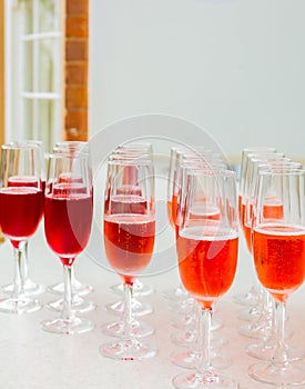 Rows of champagne flute glasses with red and orange sparkling beverage