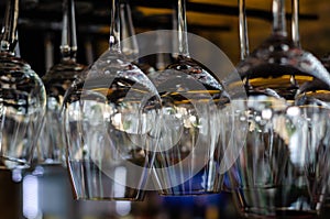 Rows of clean empty glasses above the bar counter. Interior of pub, bar or restaurant