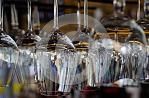 Rows of clean empty glasses above the bar counter. Interior of pub, bar or restaurant