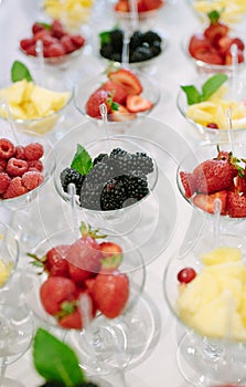 Rows of cocktail glasses with fresh summer fruits and berries