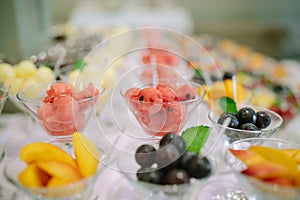 Rows of cocktail glasses with fresh summer fruits and berries