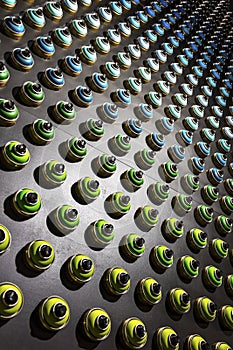 Rows of color paint spray cans placed on a black wall