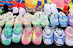 Rows of colorful knitted baby shoes on black