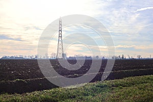 Rows of electricity pylons and power lines over cultivated fields on a winter day in the italian countryside