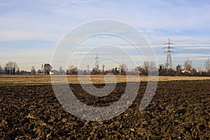 Rows of electricity pylons and power lines over cultivated fields on a winter day in the italian countryside