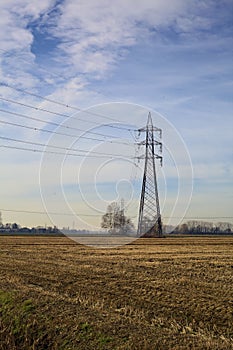 Rows of electricity pylons and power lines over cultivated fields on a winter day in the italian countryside