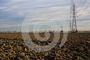 Rows of electricity pylons and power lines over cultivated fields on a winter day in the italian countryside