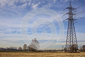 Rows of electricity pylons and power lines over cultivated fields on a winter day in the italian countryside