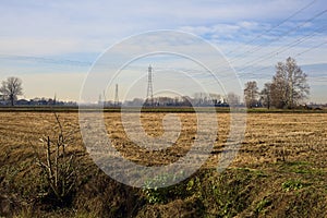 Rows of electricity pylons and power lines over cultivated fields on a winter day in the italian countryside