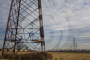 Rows of electricity pylons and power lines over cultivated fields on a winter day in the italian countryside