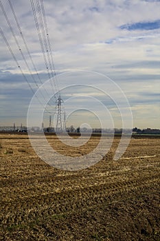 Rows of electricity pylons and power lines over cultivated fields on a winter day in the italian countryside