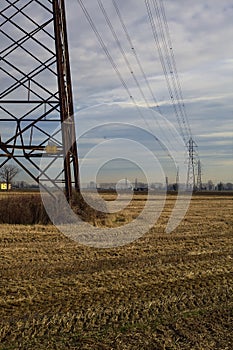 Rows of electricity pylons and power lines over cultivated fields on a winter day in the italian countryside