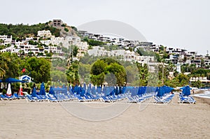 Rows of empty blue sun loungers and umbrellas on the beach. Camel Beach in Turkey