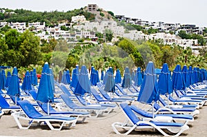 Rows of empty blue sun loungers and umbrellas on the beach. Camel Beach in Turkey