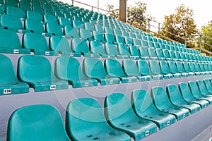 Rows of empty green plastic seats on sunny day